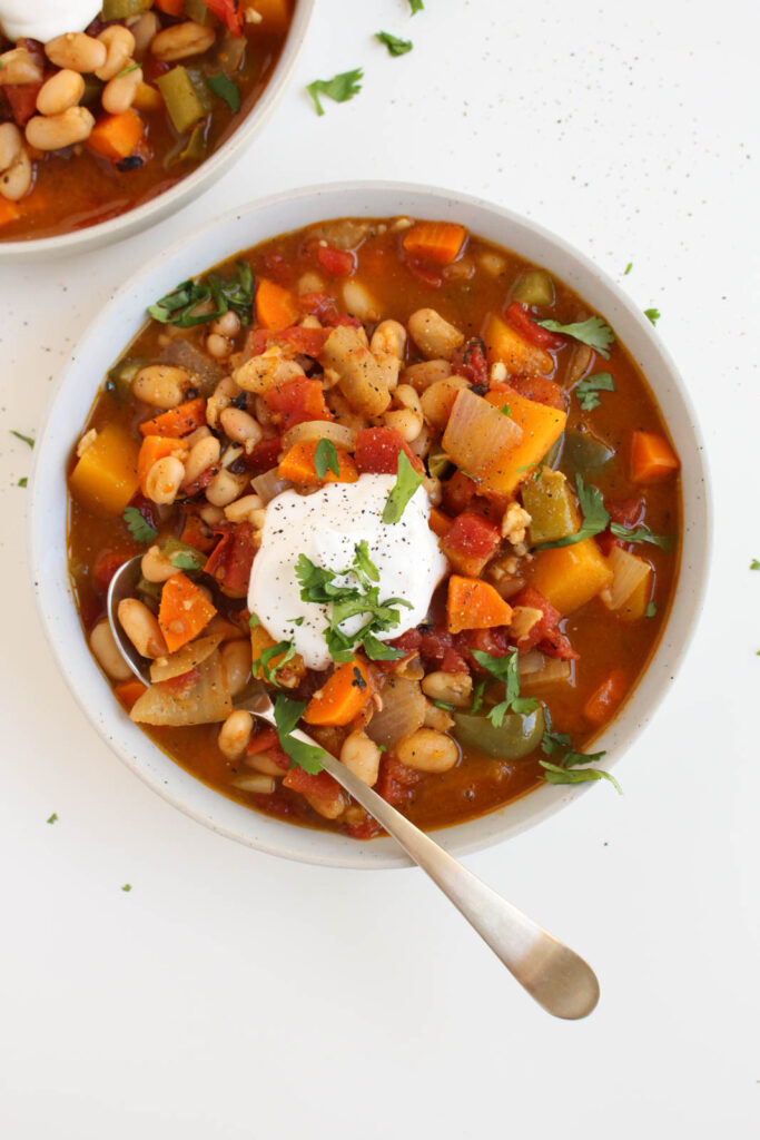overhead view of butternut squash chili in a white bowl, on a white background