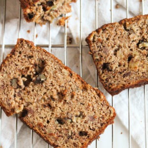 gluten-free banana nut bread slices laying a wire rack on a white background